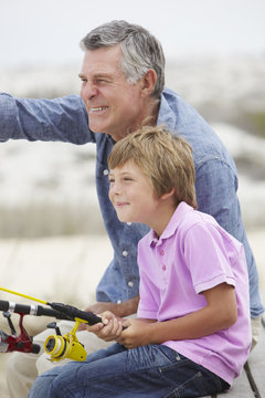 Young boy fishing with grandfather