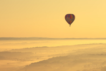 Beautiful aerial view of the Amish landscape and a hot air balloon in Pennsylvania with a gorgeous misty morning yellow sunrise