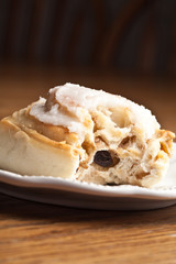 Macro shot of a homemade cinnamon roll with a bit taken out of it on an off white antique china plate