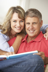 Mid age couple reading book together