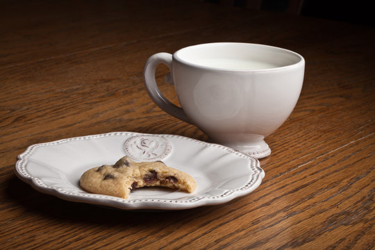 Tea party with an antique plate holding a freshly baked chocolate chip cookie with a bite taken out of it