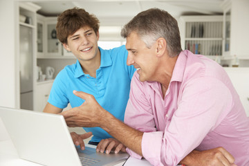 Obraz premium Father and teenage son using laptop