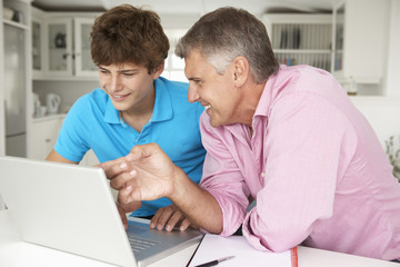 Father and teenage son using laptop