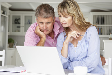Fototapeta na wymiar Mid age couple working at home on laptop