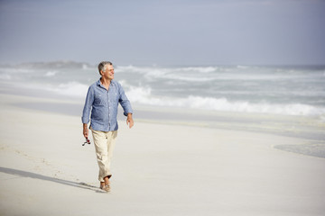 Senior man walking on beach - Powered by Adobe
