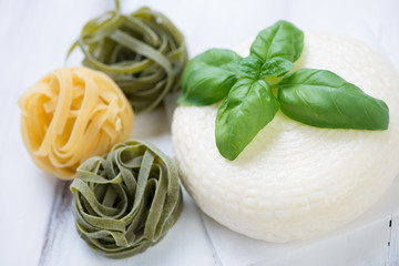 Close-up of coloured tagliatelle, cheese and green basil