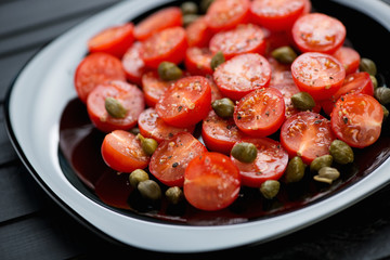 Glass plate with tomatoes, capers, sea salt and black pepper