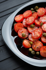 Salad with red tomatoes, capers, sea salt and black pepper