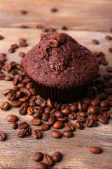 Chocolate muffin and coffee grains on wooden background