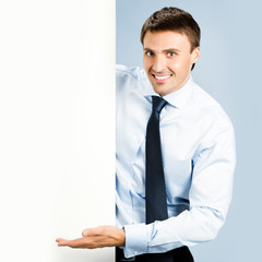 Business man showing blank signboard, over blue