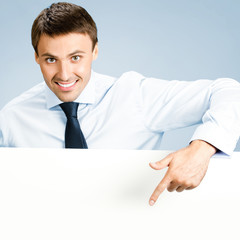 Business man showing blank signboard, over blue