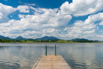 wooden boardwalk into lake hopfen in bavaria at sunny blue sky