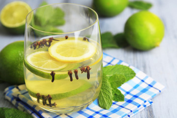 Fresh summer drink with lime and cloves in glass,
