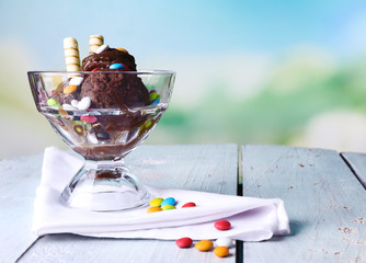 Chocolate ice cream with multicolor candies and wafer rolls in