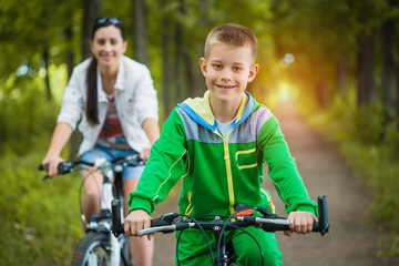 Fototapeta premium Happy family. mother and son riding bicycle in the park