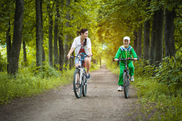 Fototapeta premium Happy family. mother and son riding bicycle in the park