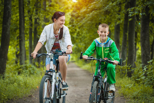 Happy Family. Mother And Son Riding Bicycle In The Park