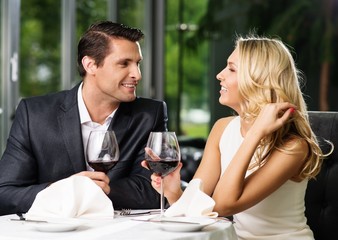 Cheerful couple in a restaurant with glasses of red wine