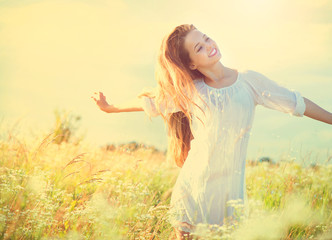 Beauty model girl in white dress having fun on summer field