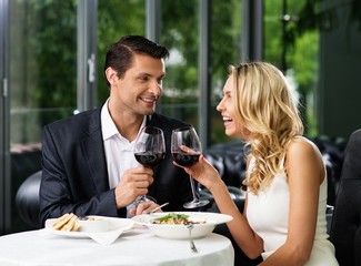 Cheerful couple in a restaurant with glasses of red wine