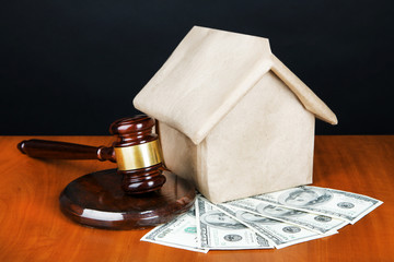 Gavel,model of house and money on table on black background