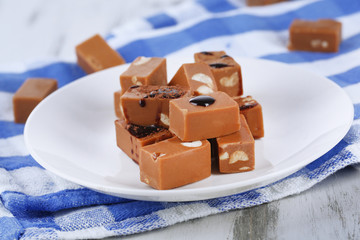 Many toffee on plate on napkin on wooden table