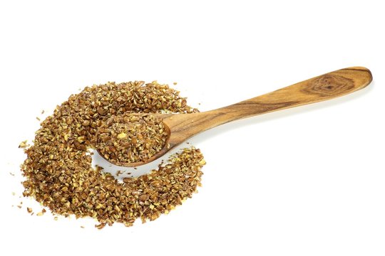 Leinsamenschrot mit einem L&ouml;ffel aus Olivenholz isoliert auf wei&szlig;em Hintergrund