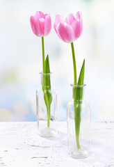 Beautiful tulips in bucket in vase on table on light background