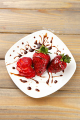 Red ripe strawberries with chocolate on wooden table
