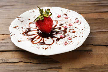 Red ripe strawberry with chocolate on wooden table