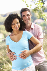 Expectant couple outdoors in countryside