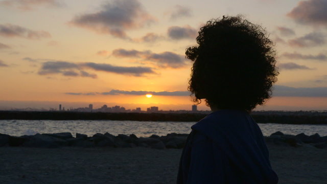 Woman looking over ocean as sun goes down