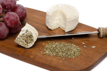 Goat cheese, grapes and provencal herbs on a wooden cutting boar