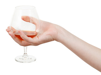 hand holds glass goblet with brandy