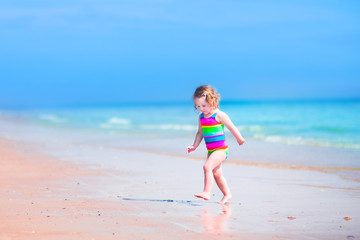 Fototapeta na wymiar Little girl running on a beach
