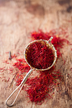 saffron spice in rustic sieve on old wooden background, closeup