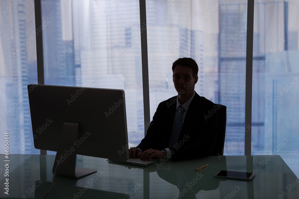 Poster businessman working overtime at computer desk