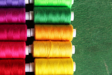 Multicolor sewing threads on wooden background