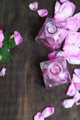 Rose oil in bottles on color wooden background