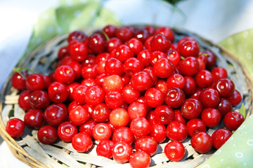 Sweet cherries on wicker stand on fabric background