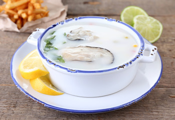 Tasty soup with oysters on wooden table
