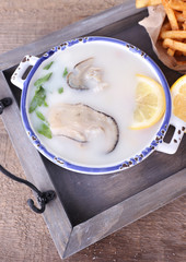 Tasty soup with oysters on wooden table
