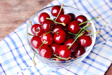 Cherries in color bowl on wooden background