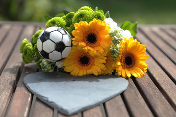 Blumen mit Fußball auf Holztisch