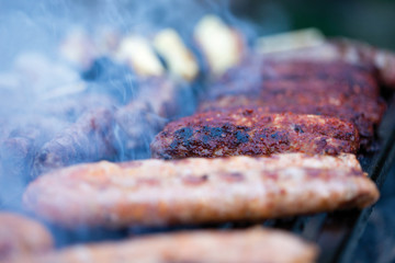pork and beef sausages cooking over the hot coals on a barbecue