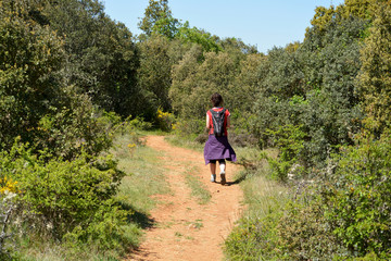 mujer caminando por un camino en el monte en verano