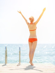 Young woman on bridge rejoicing. rear view