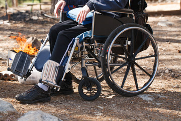 Obraz premium Man in a wheelchair in a park near the fire.