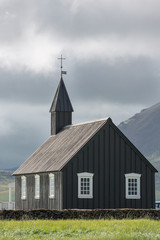 Fototapeta na wymiar Cloudy sky, dark church in Budir, Iceland
