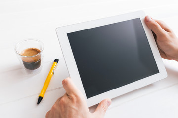Hands of a man holding blank tablet device over wooden table
